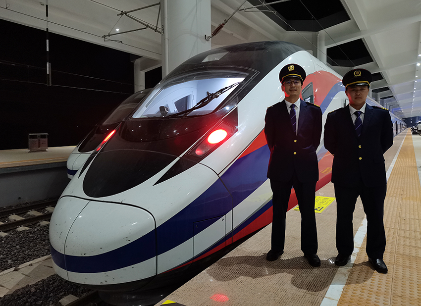 劉銀能（右一）與中國師父鄔俊鴻在動車組前合影。受訪者供圖